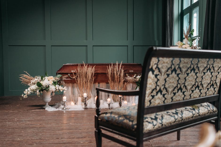 A decorated interior scene featuring a wooden table with floral arrangements and candles, set against a dark green paneled wall. On the left side, there is a white ceramic vase holding a delicate arra